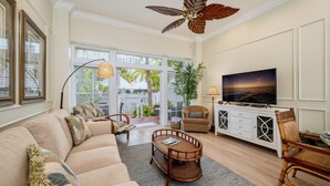 A spacious living room with a large sofa, a television, and a ceiling fan. - **CARIBBEAN CHARM** Villa Near Duval & Beach + Last Key White Glove Service... (Key West)