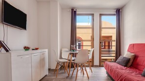 Un espacio habitable pequeño con kitchenette, comedor y un sofá rojo.