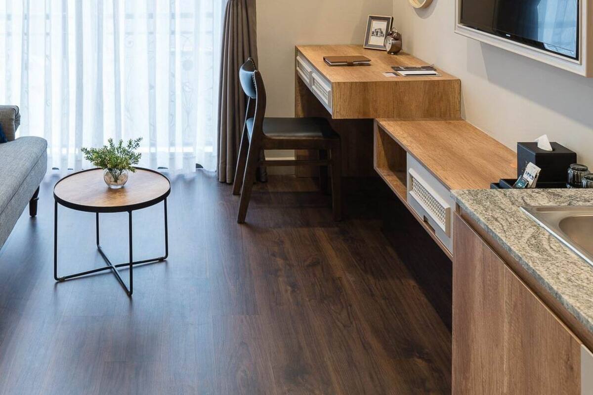 A hotel room with a bed, sofa, round table, desk, and TV.