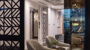 A modern interior with a geometric patterned floor, two upholstered armchairs, a small table with a vase, and a decorative ceiling light. - Charmaine's Hotel & Apartment (Ho Chi Minh City)
