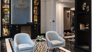 A lobby with a chandelier, a reception desk, and two armchairs. - Charmaine's Hotel & Apartment (Ho Chi Minh City)