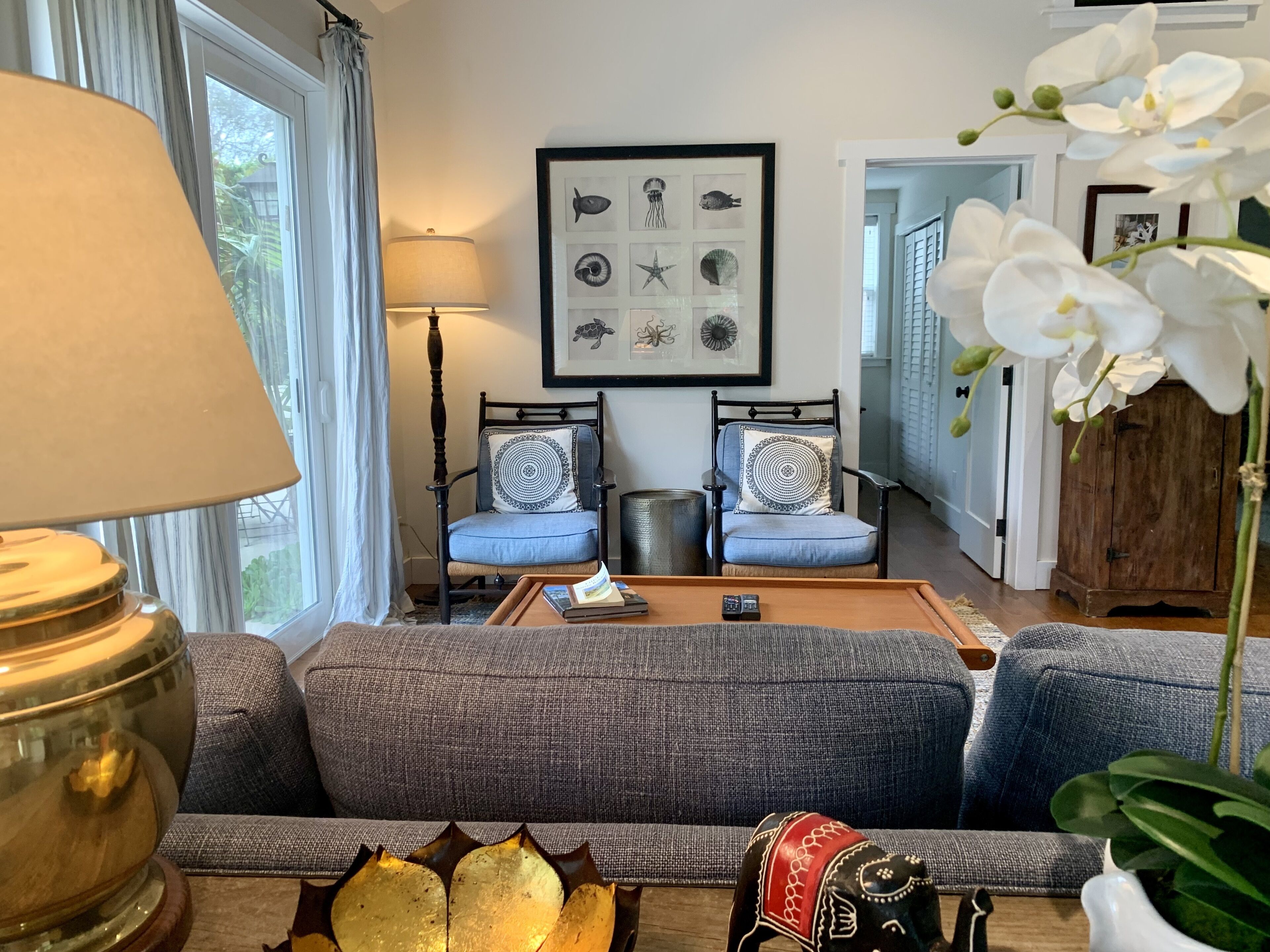 Ein Wohnzimmer mit einer Couch, zwei Sesseln, einem Couchtisch, einer Lampe und einem gerahmten Bild an der Wand.