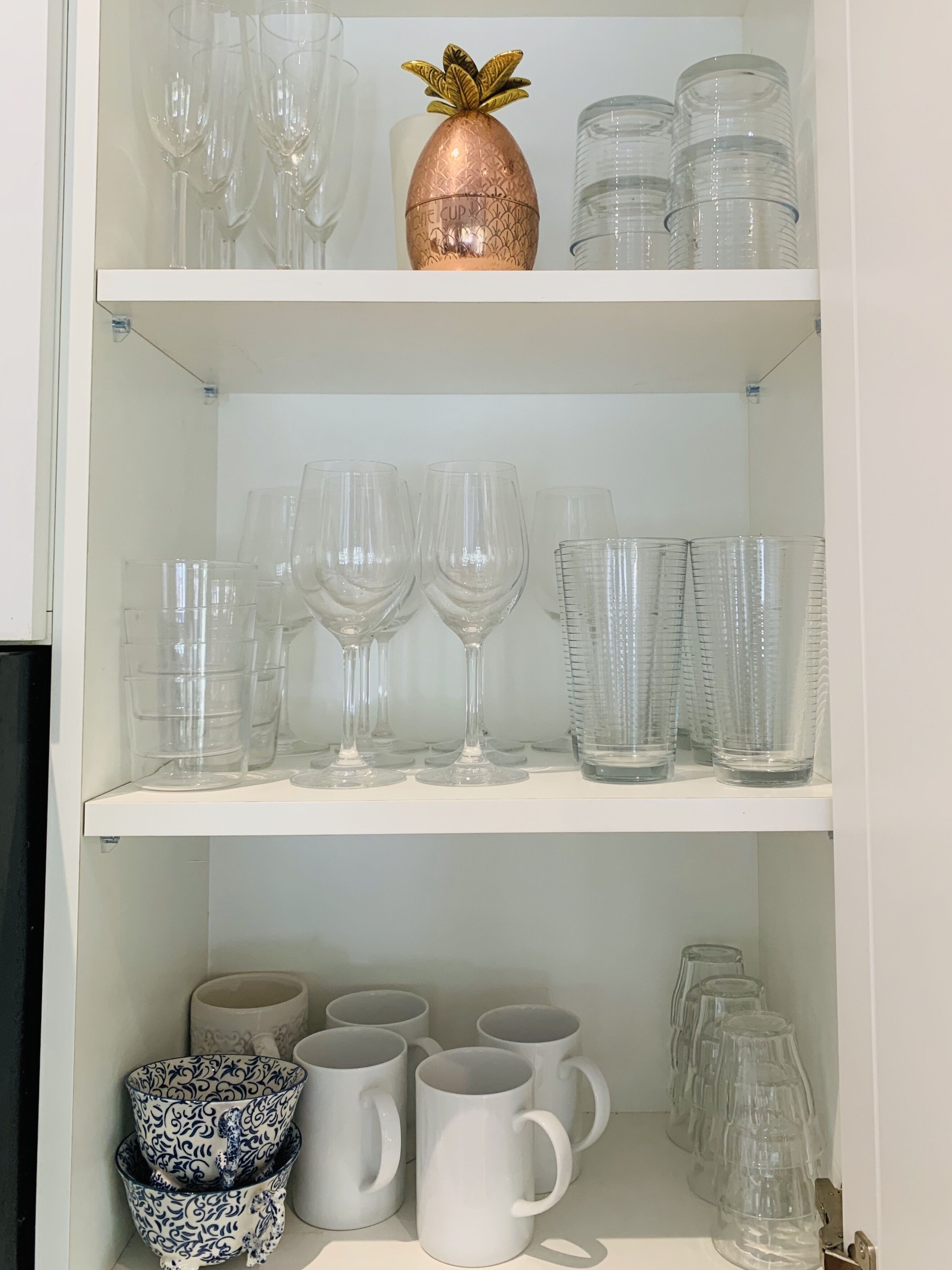 Ein Regal mit verschiedenen Gläsern, darunter Weingläser, Tumbler und Tassen.