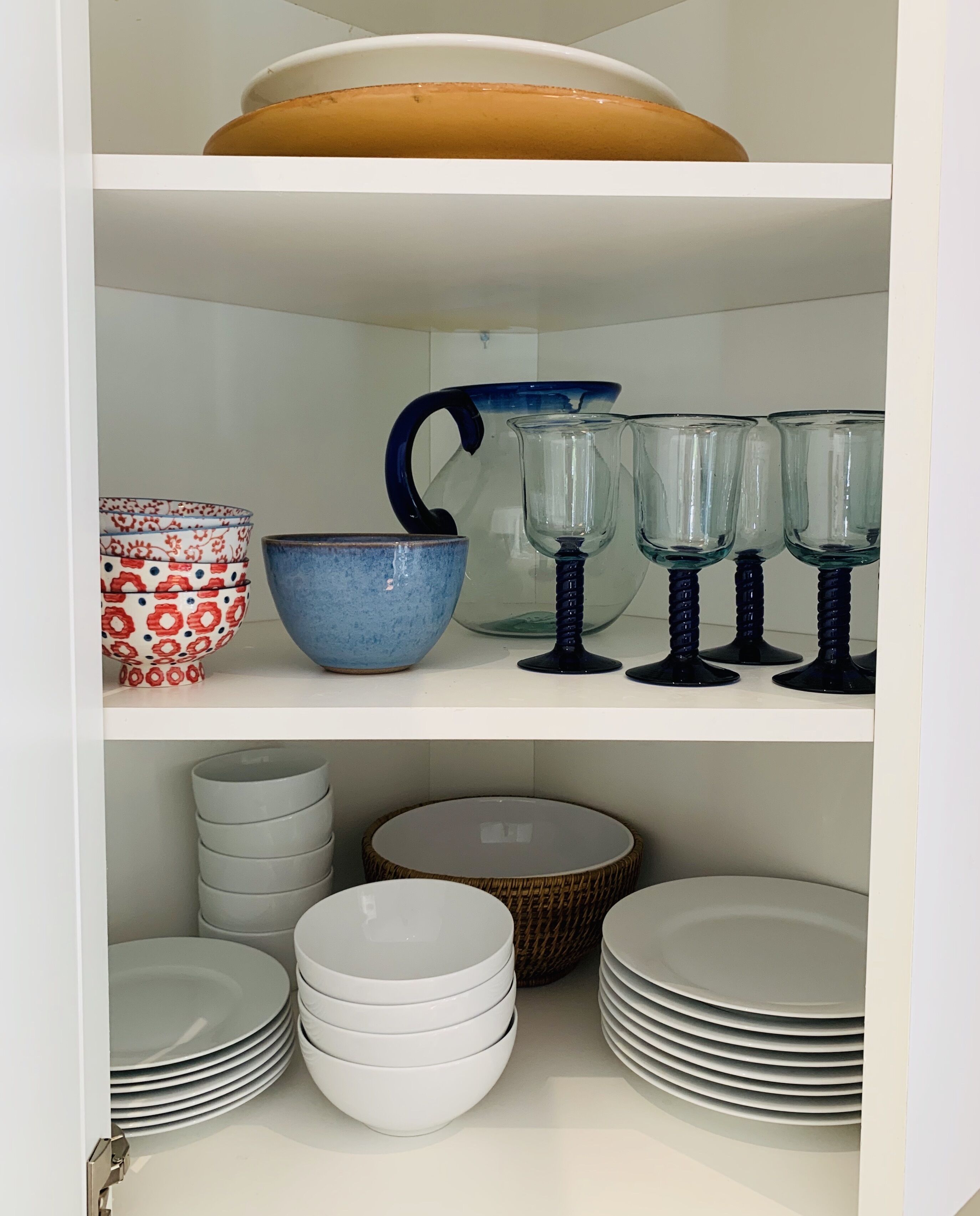 A kitchen cabinet with various dishes and glassware.