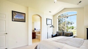 Una camera da letto con un letto grande, una scrivania e una finestra vista alberi.
