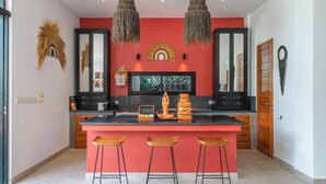Una cocina moderna con pared de acento roja, armarios negros y una isla central con taburetes de bar.