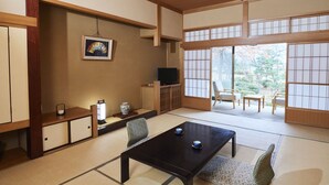 A traditional Japanese room with tatami flooring, a low table, chairs, a television, and a sliding door leading to an outdoor area. - Sagiya Sensorai (Kaminoyama)