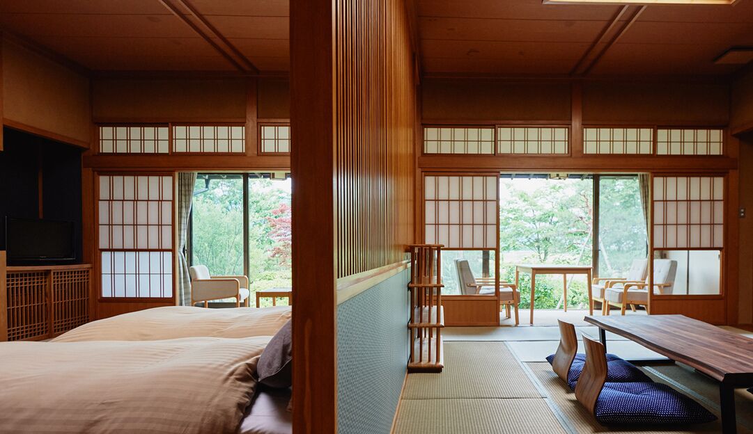 A traditional Japanese-style room with tatami flooring, a low table, and a bed.