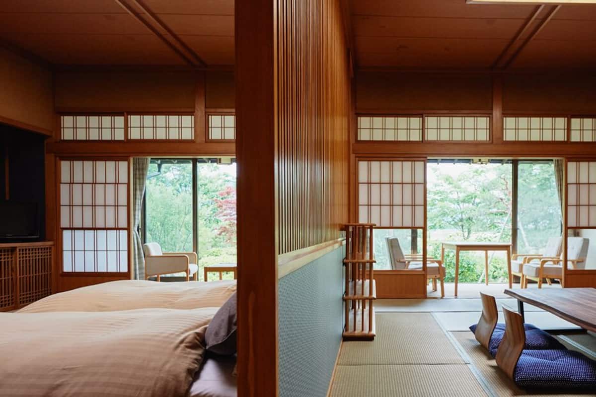 Una habitación tradicional japonesa con suelo de tatami, una mesita baja y una cama.