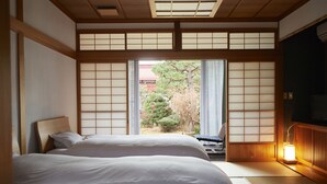 A traditional Japanese-style bedroom with tatami flooring, a low wooden bed, and sliding shoji doors. - Sagiya Sensorai (Kaminoyama)