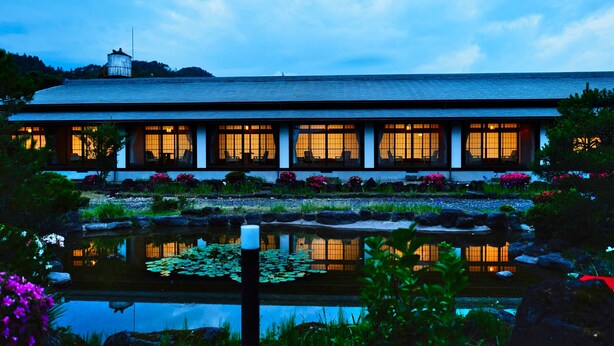 A traditional building with a long roof and multiple windows, surrounded by a garden with a pond and various plants. - Sagiya Sensorai (Kaminoyama)