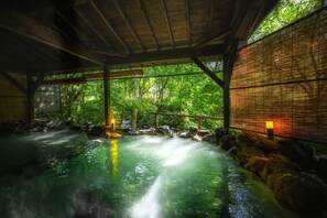 A traditional Japanese onsen with a wooden interior, a stone bath, and a bamboo screen. - Bandai Meito Resort Bonari no Mori (Inawashiro)