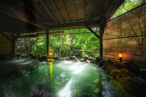 Uma onsen japonesa tradicional com interior de madeira, banheira de pedra e um biombo de bambu.