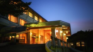 Un hotel moderno con una entrada curva, múltiples ventanas y una escalera que conduce a la entrada.