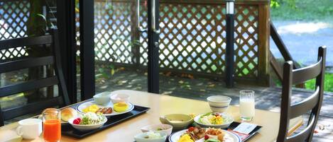 A breakfast tray with various dishes and drinks on a wooden table outdoors.