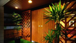 Pared de madera con un diseño geométrico, una planta en maceta y una escalera.