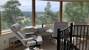 A room with a view of a forest and mountains, furnished with two white chairs and a small table. - Hilltop ocean view round house (Florence)