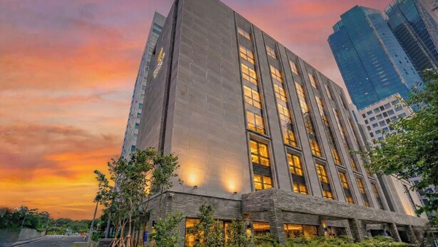 A modern high-rise building with a prominent entrance and large windows. - Haeundae Thevan Hotel (Busan)