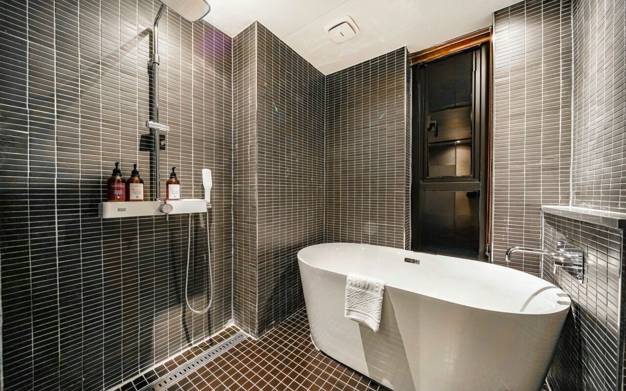A modern bathroom with a freestanding bathtub, a shower area, and a vanity with toiletries.