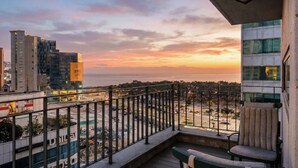 A balcony with a view of the sea and cityscape at sunset. - Haeundae Thevan Hotel (Busan)