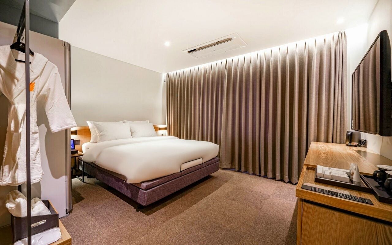 Une chambre d’hôtel comprenant un lit, un bureau avec un ordinateur, une télévision et une armoire.