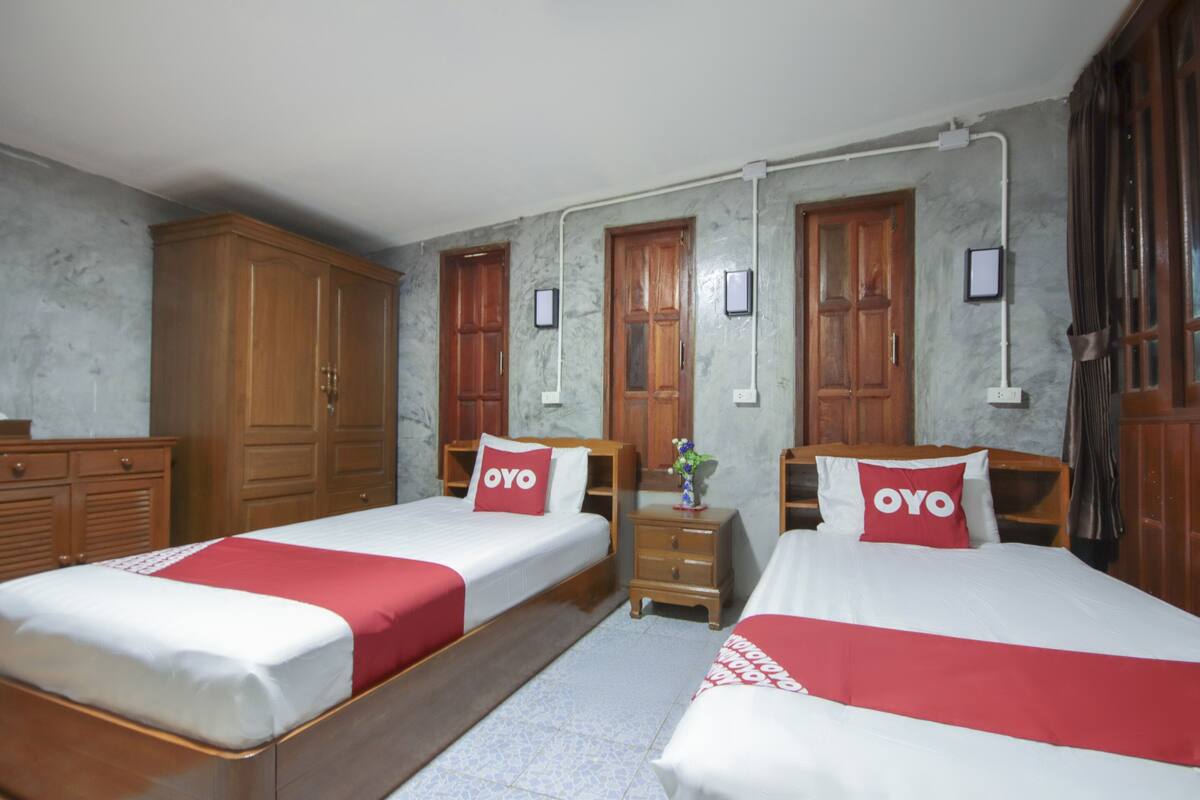Quarto de hotel com duas camas, armários de madeira, paredes de mármore e chão em mosaico.