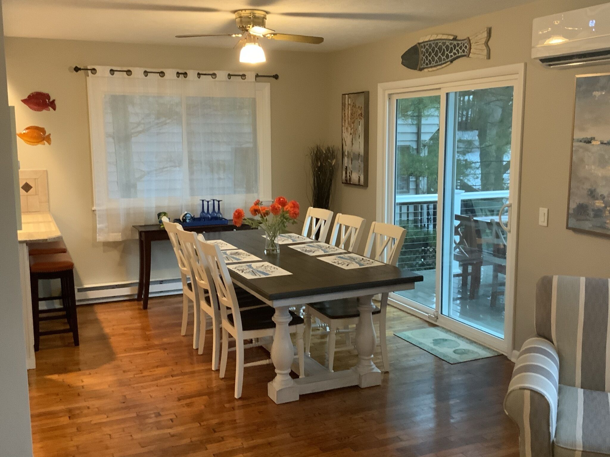 A dining area with a wooden table, white chairs, and a ceiling fan.