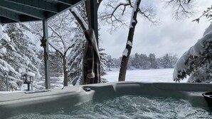 Ett bubbelbad utomhus, omgivet av snö, med utsikt över ett snötäckt landskap.
