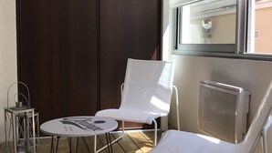 Parvekkeella on kaksi valkoista tuolia, pieni pyöreä pöytä ja metallinen lyhty.