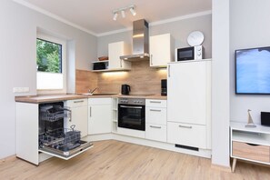 A modern kitchen with white cabinets, a built-in oven, a microwave, and a dishwasher.