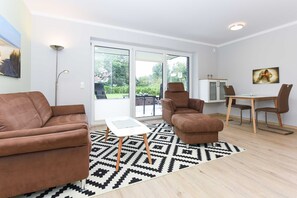 A modern living room with a brown sofa, a white coffee table, and a patterned rug.