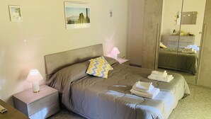 A neatly arranged bedroom with a bed, bedside tables, a mirror, and artwork on the walls.