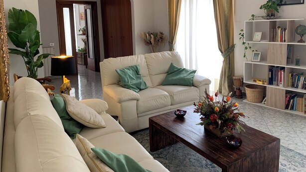 A living room with a beige sofa, a wooden coffee table, and a bookshelf.