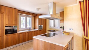 Cozinha moderna com armários de madeira, uma ilha central e uma janela ampla.