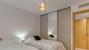A modern bedroom with two beds, a bedside table, a lamp, and a wooden door. - Domaine Aïga by Interhome (Hossegor)