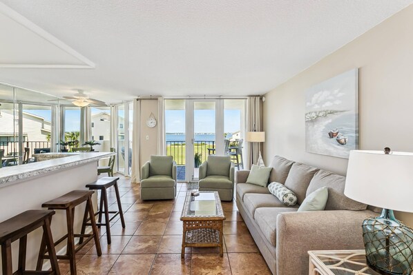 A living room with a sofa, chairs, a coffee table, and a bar area with stools.
