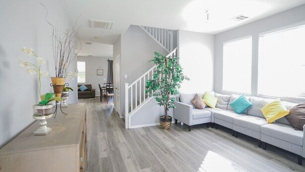 Un salon moderne avec un canapé gris, un escalier et un coin repas.