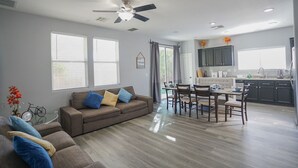 Un salon moderne avec un canapé, une table à manger et des chaises. Il y a également un coin cuisine avec des placards et une fenêtre.