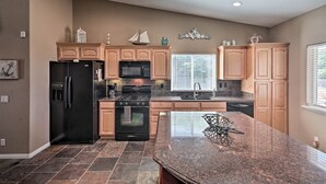 Una cocina con isla de granito, electrodomésticos de acero inoxidable y armarios de madera.