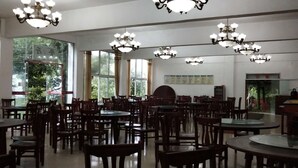 A dining area with multiple tables and chairs, chandeliers, large windows, and a bulletin board on the wall. - Jingheyuan Mianzhu (Deyang)