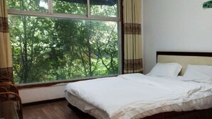 A room with a bed, a window with curtains, and a small table. - Jingheyuan Mianzhu (Deyang)