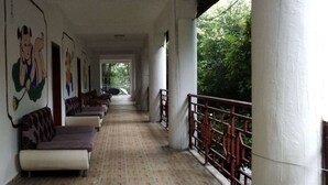 A covered corridor with rows of sofas and chairs, large pillars, and a railing overlooking greenery. - Jingheyuan Mianzhu (Deyang)