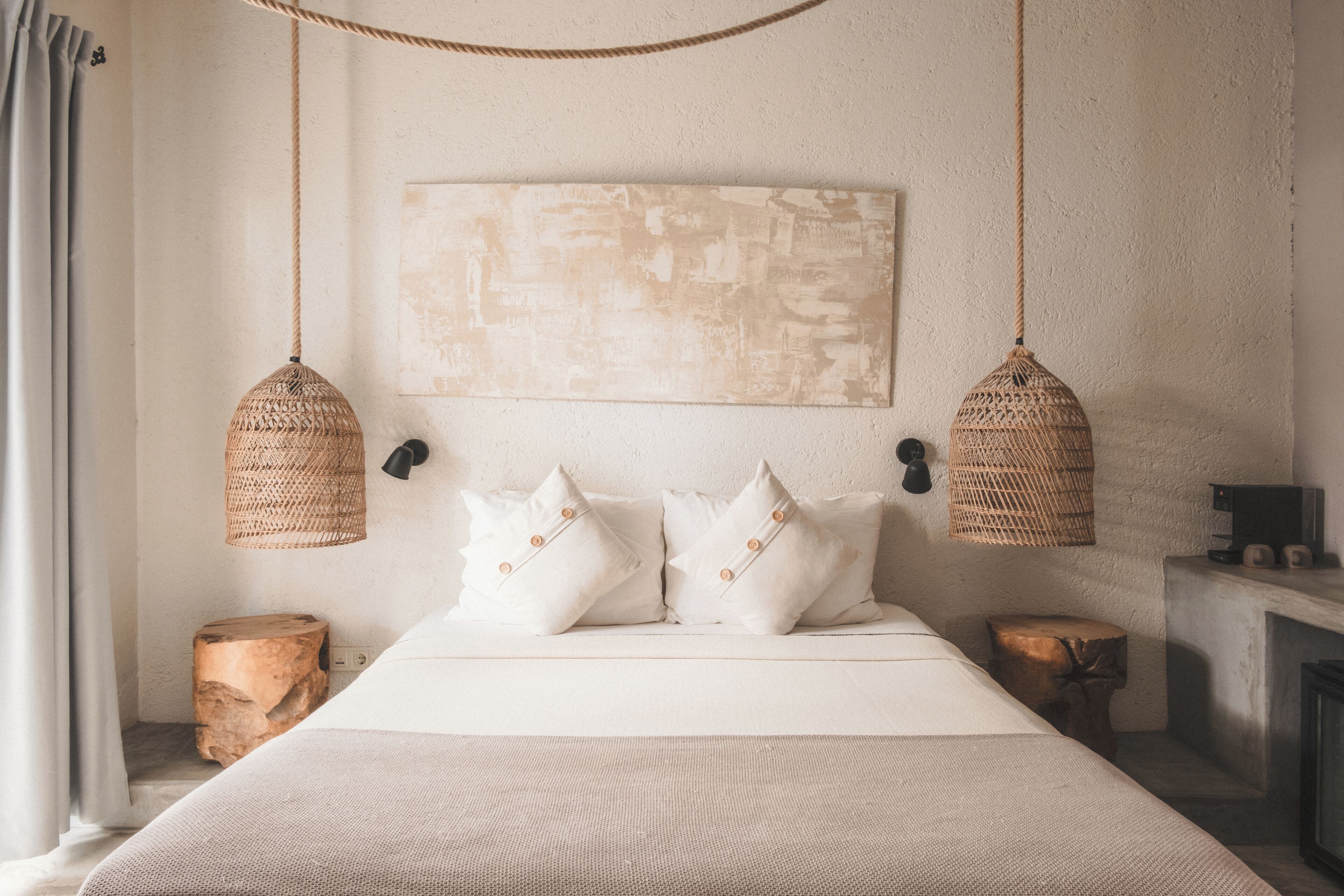 Een slaapkamer met een groot bed, twee hangende geweven lampen, een houten nachtkastje en een open haard.