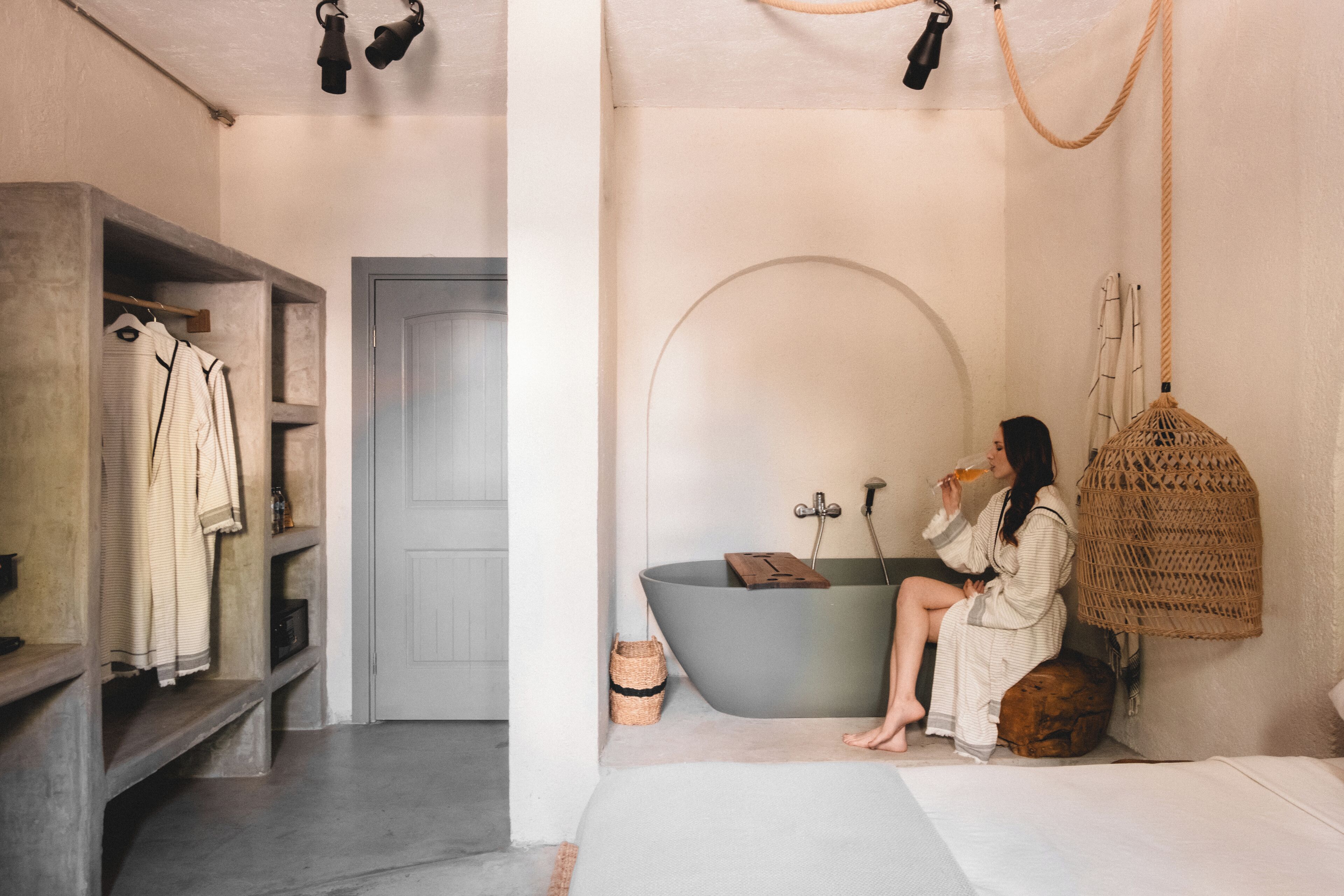 A bathroom with a bathtub, a hanging basket, and a shelf with towels.