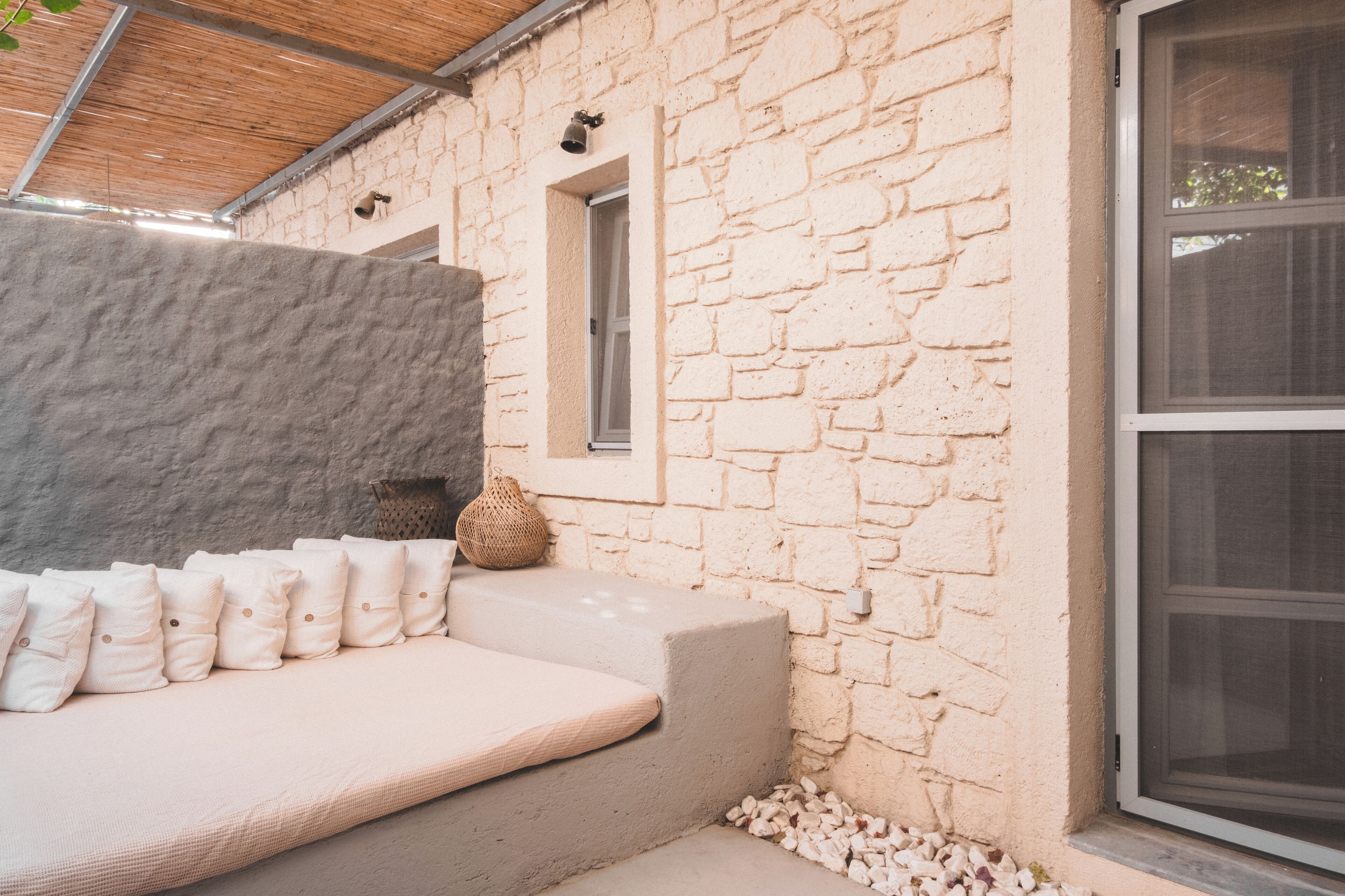 A stone exterior wall with a window, a stone bench, and a wicker basket.