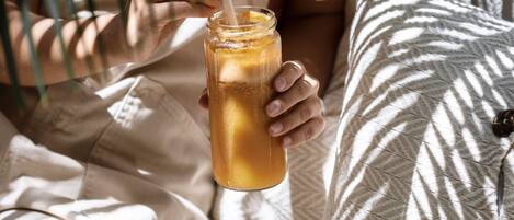 A person sitting on a bed with a pillow, holding a glass with a straw.