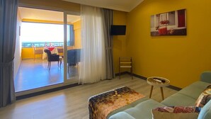 Una sala de estar con sofá, una mesita y vista a un balcón con mesa y sillas.
