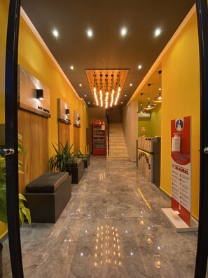 Un vestíbulo de hotel con piso de mármol, mostrador de recepción de madera y un refrigerador de Coca-Cola.
