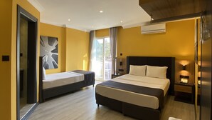 Una habitación de hotel con dos camas, piso de madera, un ventanal grande y un aire acondicionado instalado en la pared.
