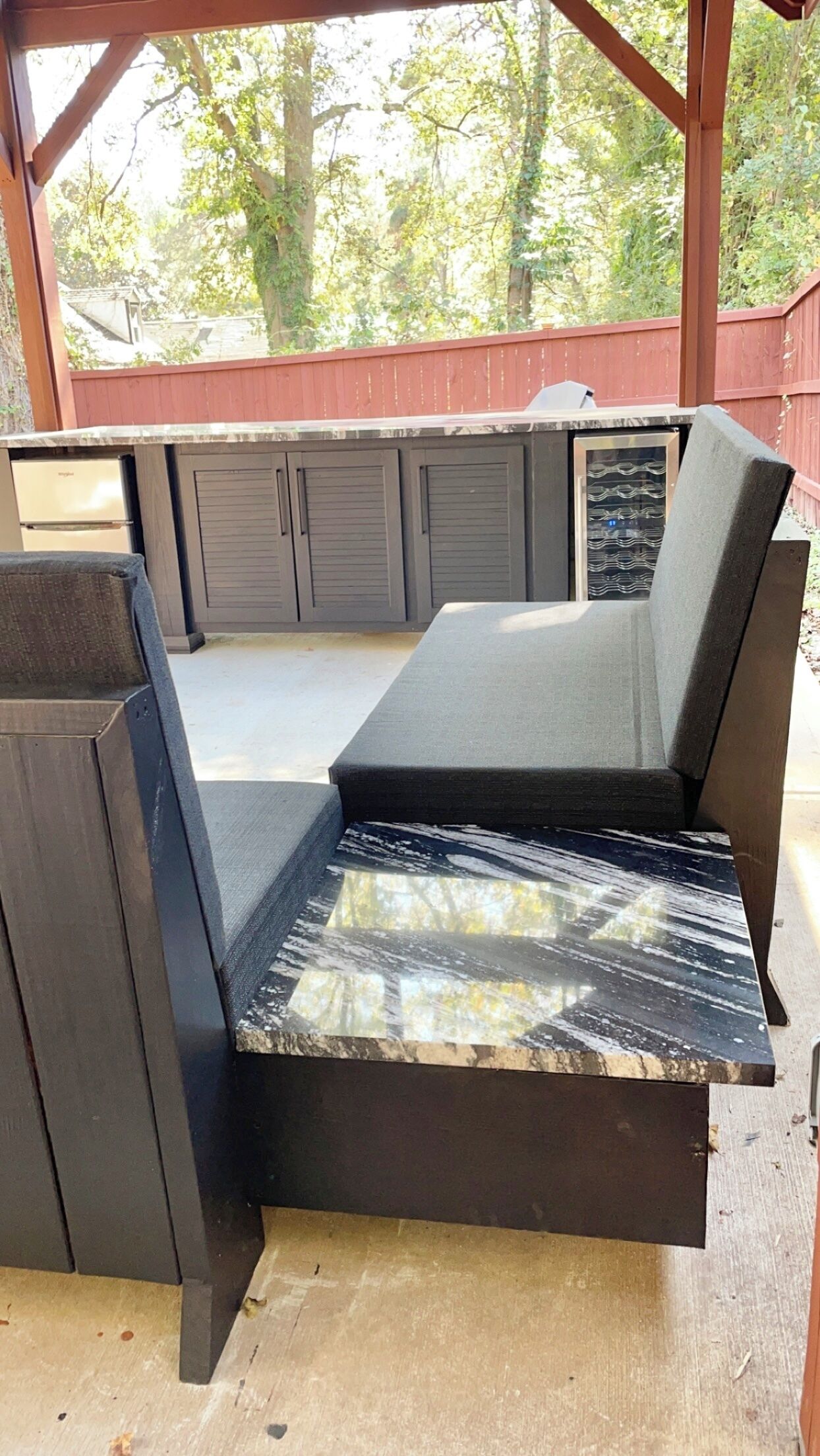 A covered outdoor kitchen area with a built-in grill, seating, and a countertop.